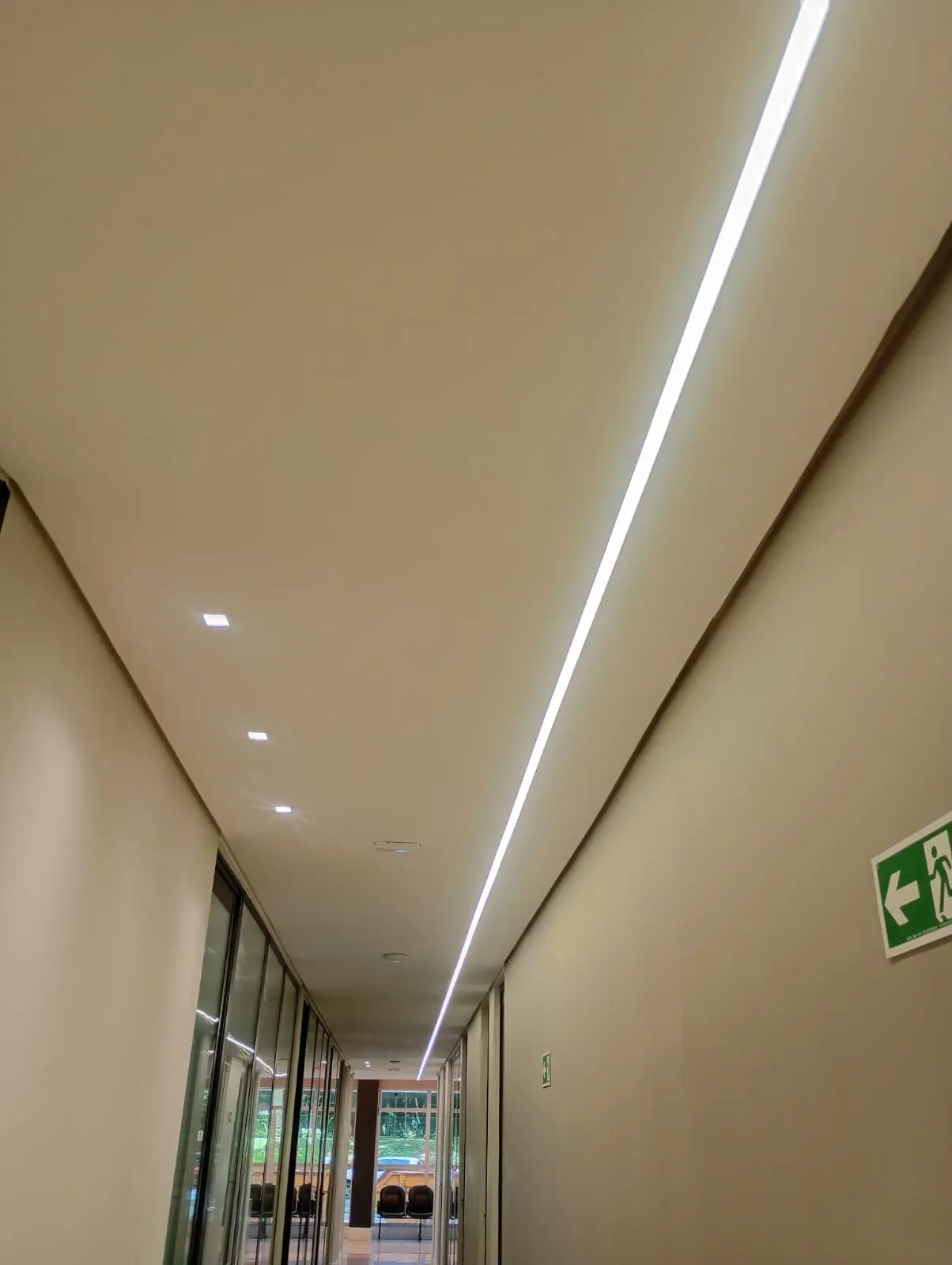 Corredor com linhas de LED embutidas e spots no teto.