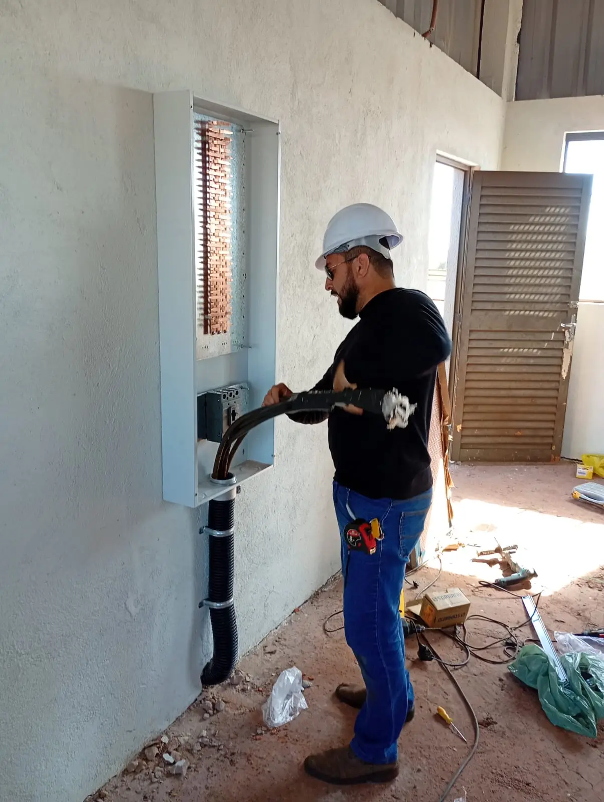 Eletricista ajustando infraestrutura elétrica embutida na parede.