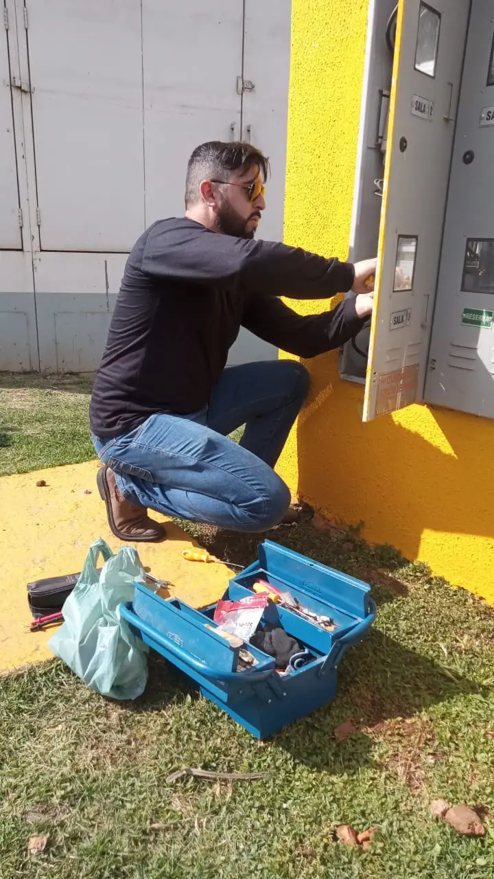 Eletricista executando manutenção em painel elétrico externo.