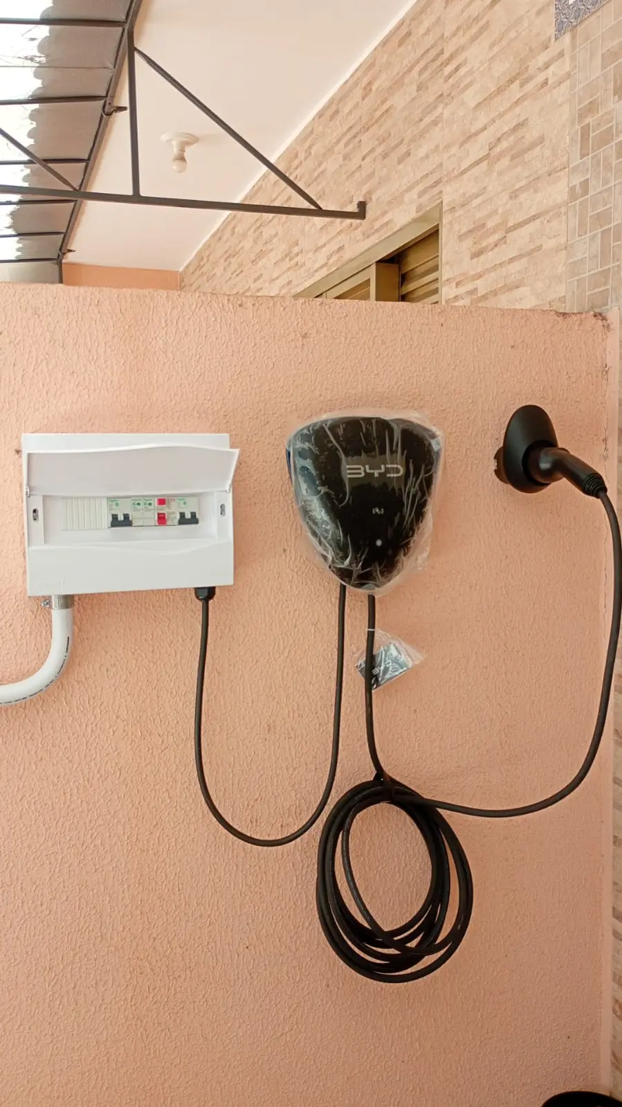 Carregador de veículo elétrico e quadro de disjuntores na parede externa.