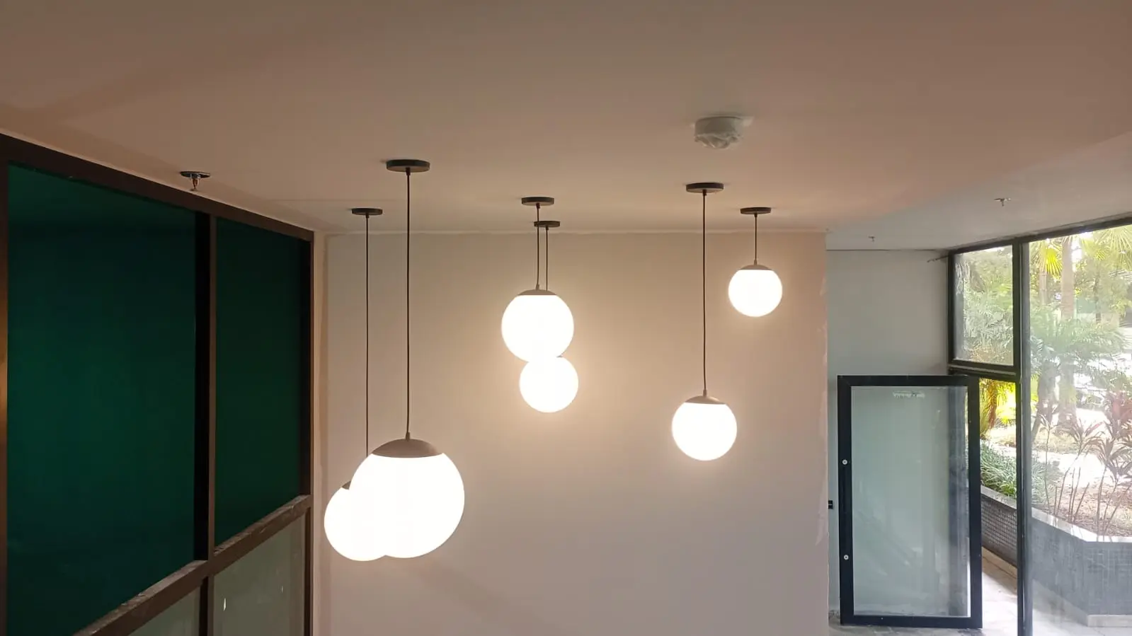 Ambiente interno com luminárias pendentes instaladas e acesso ao exterior.