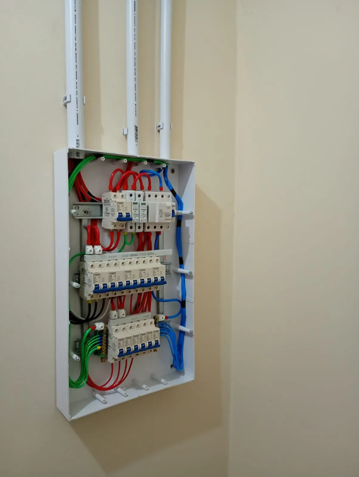 Quadro elétrico embutido aberto com disjuntores e cabeamento.