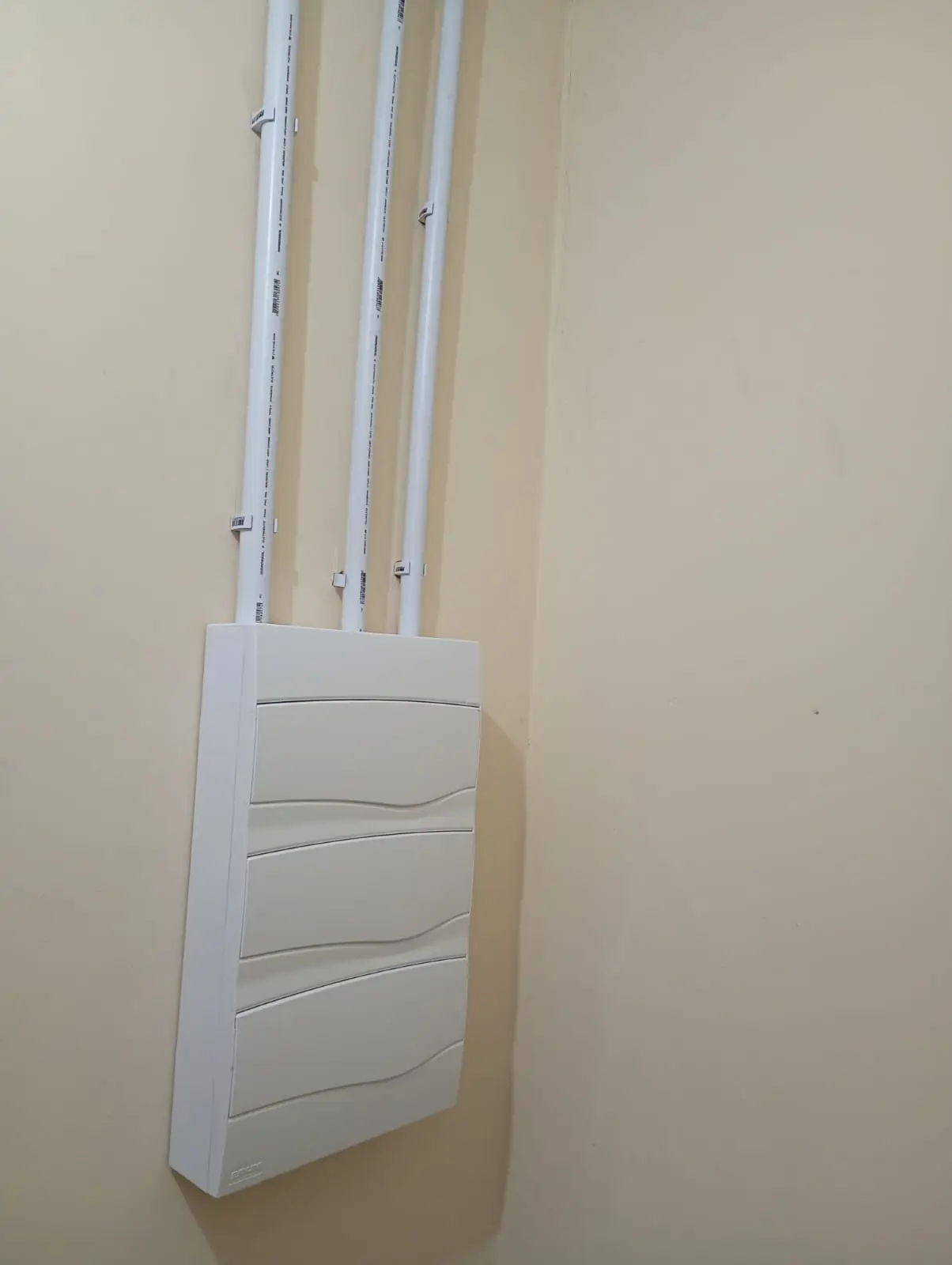 Conjunto de quadros elétricos fechados com acabamento branco.