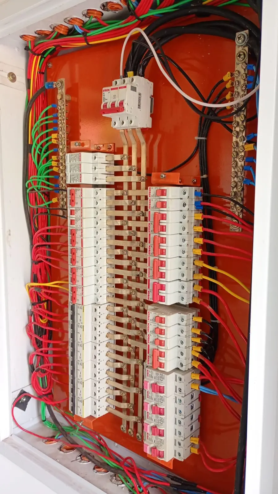 Painel elétrico vermelho com barramentos e cabeamento organizado.