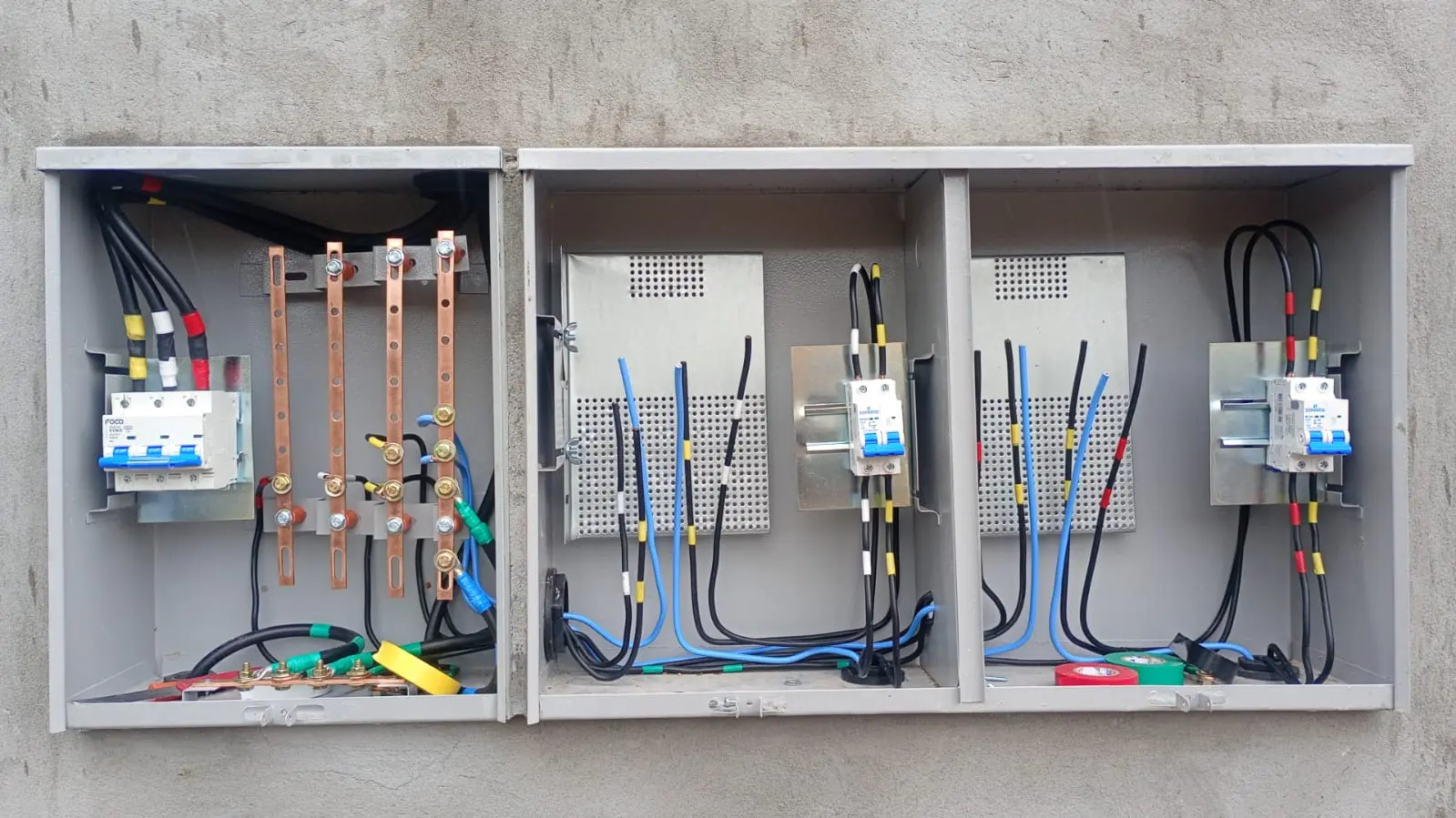 Conjunto de quadros elétricos abertos com disjuntores e cabeamento.