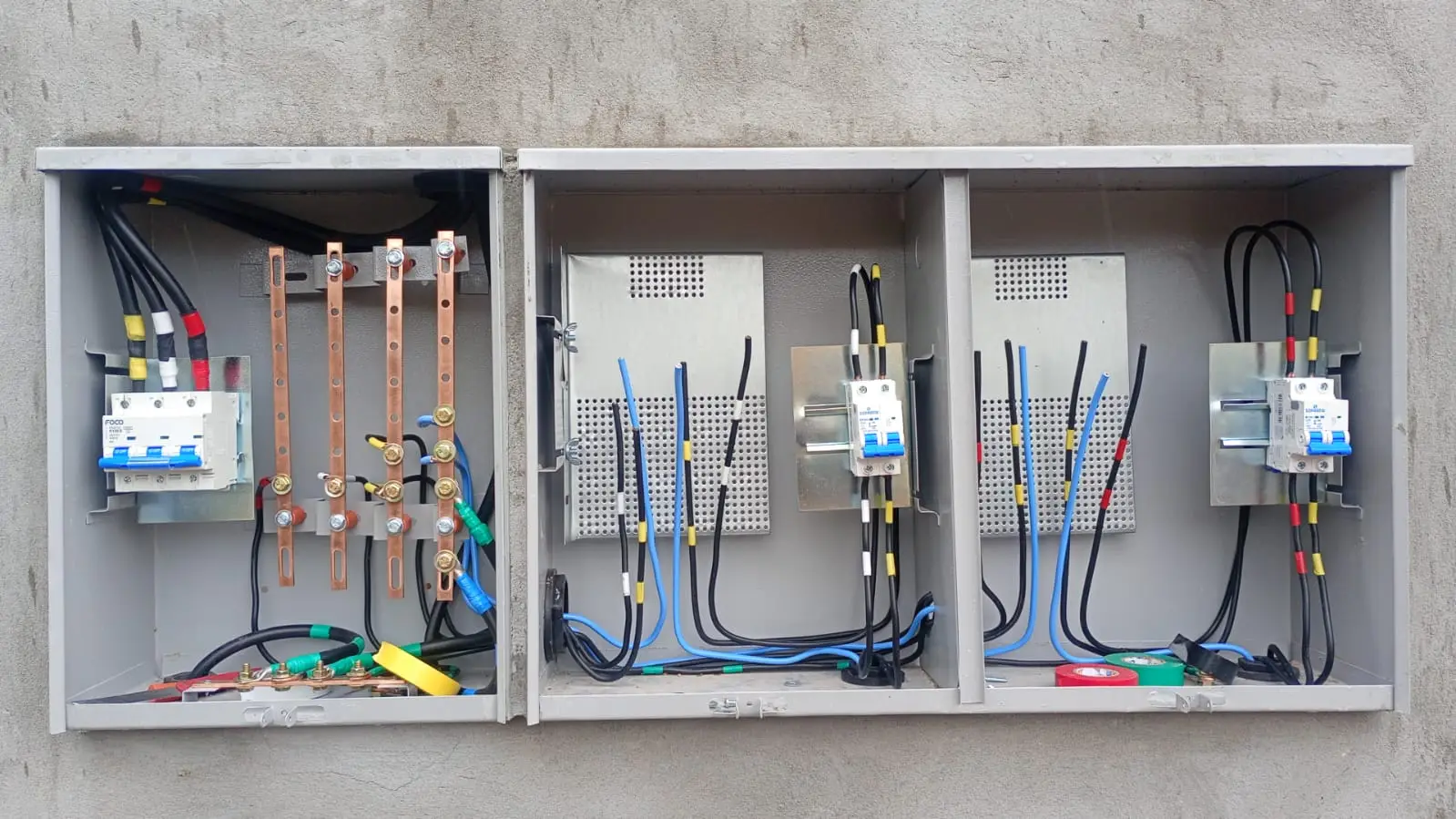 Conjunto de quadros elétricos abertos com cabeamento instalado.
