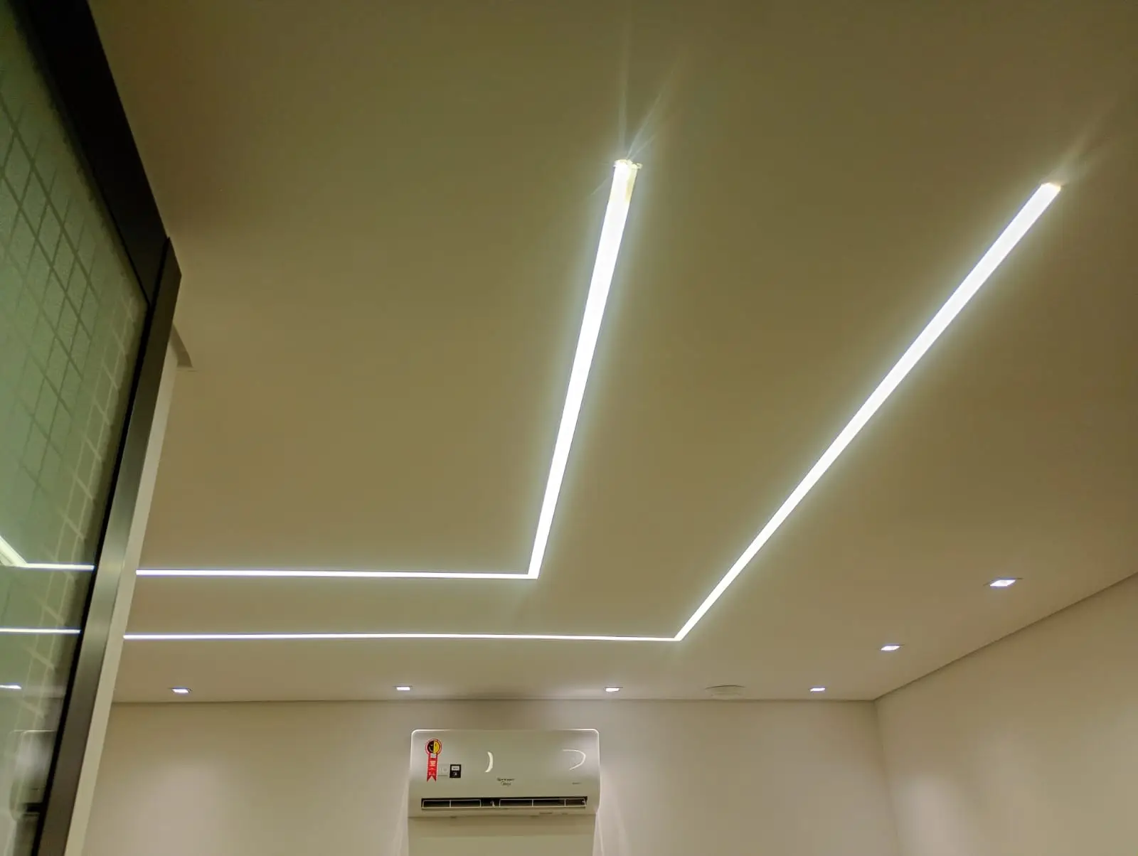 Teto com linhas retangulares de LED e spots embutidos.